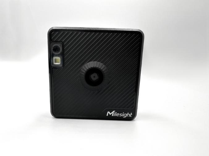 A black square camera with a lensDescription automatically generated